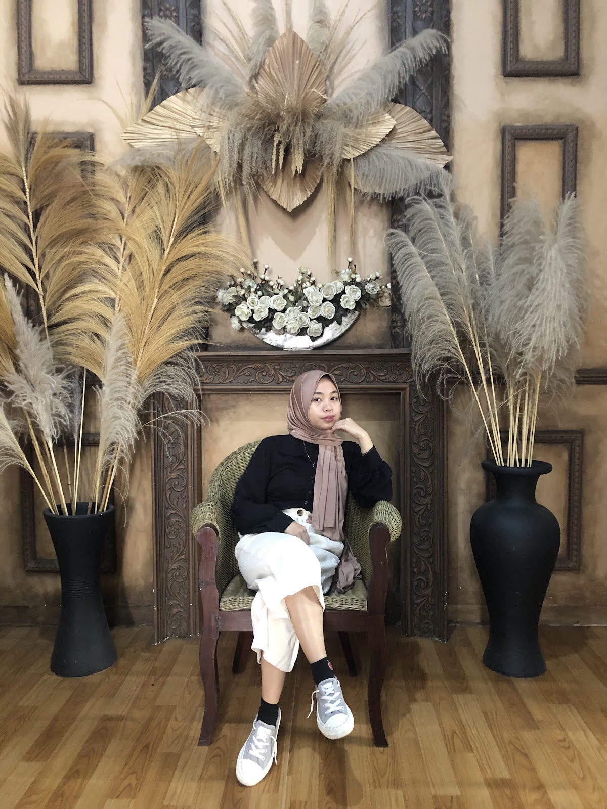 Foto personal di kursi dengan latar pampas dan panel bernuansa kayu