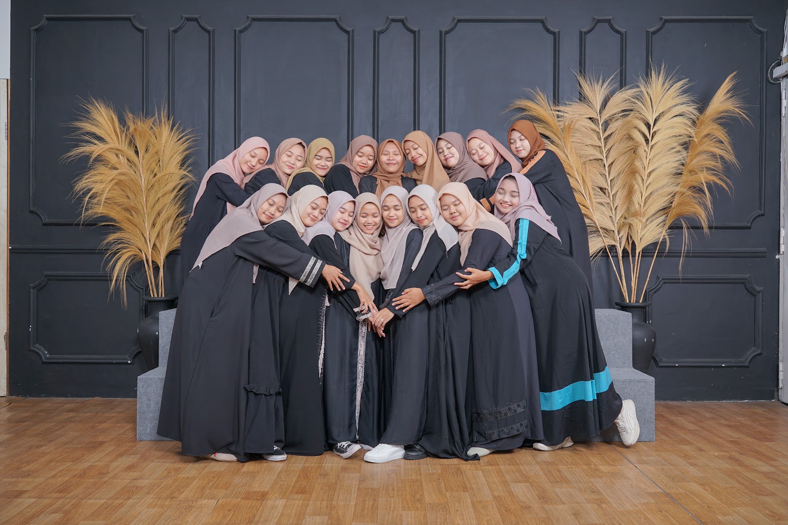 Foto grup di depan dinding gelap dengan pampas di kedua sisi